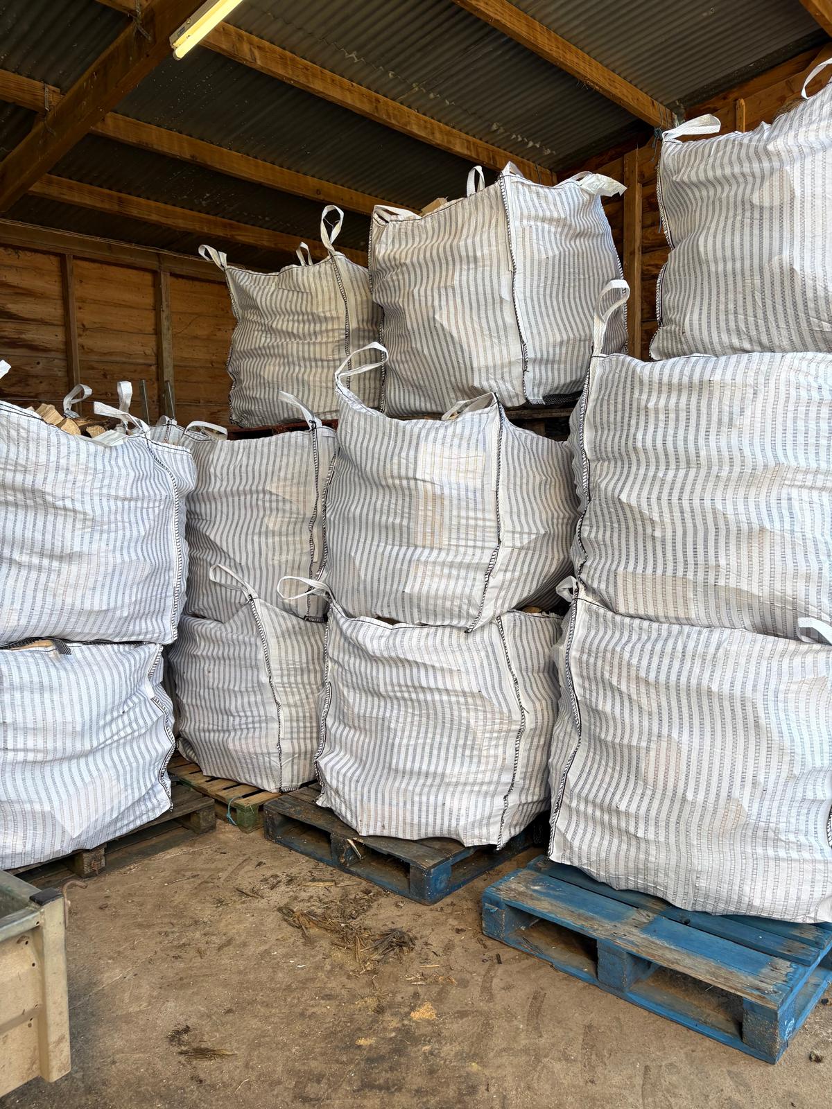 Stacked dumpy bags of seasoned firewood stored in the barn